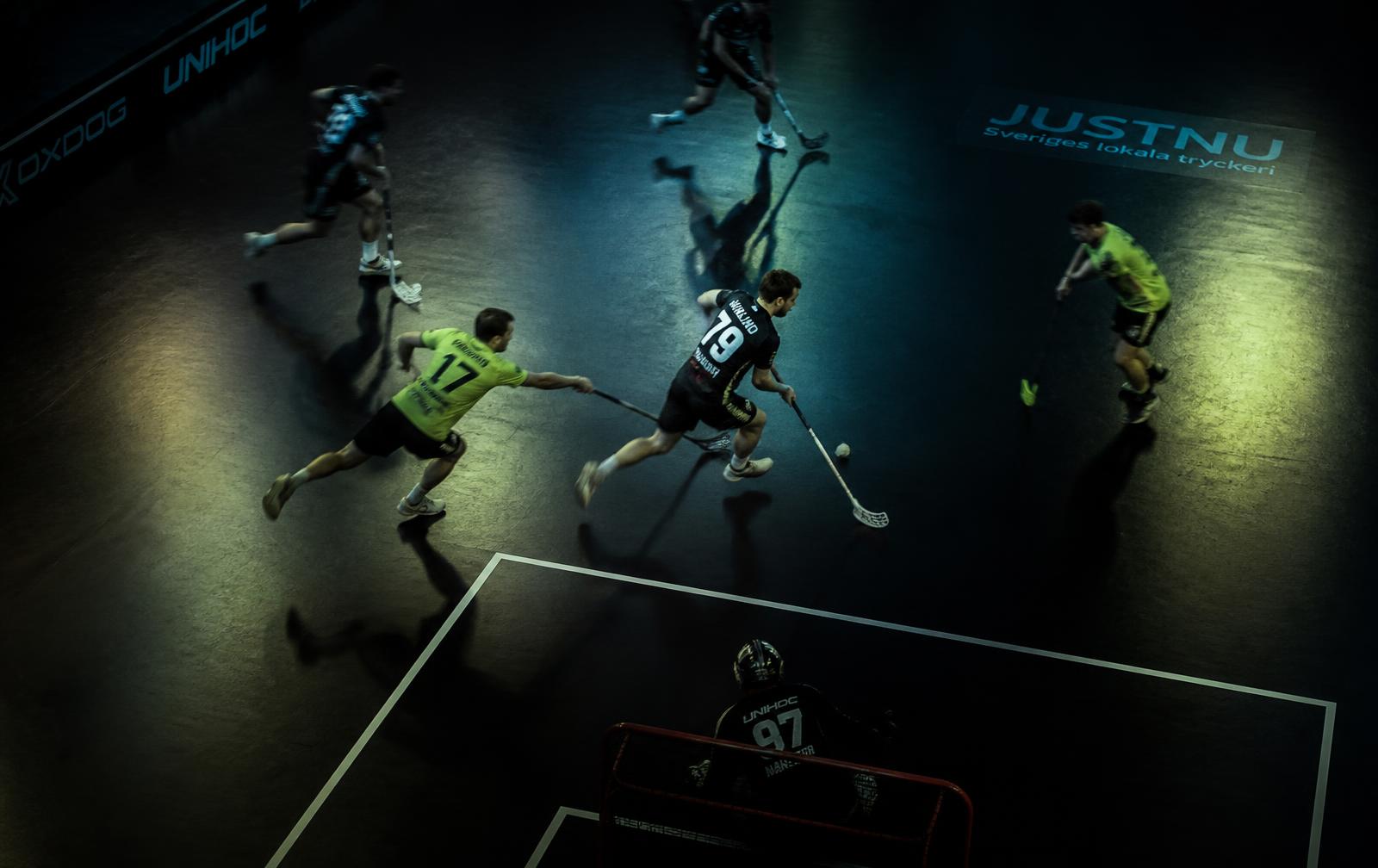 Floorball players in motion during an indoor match